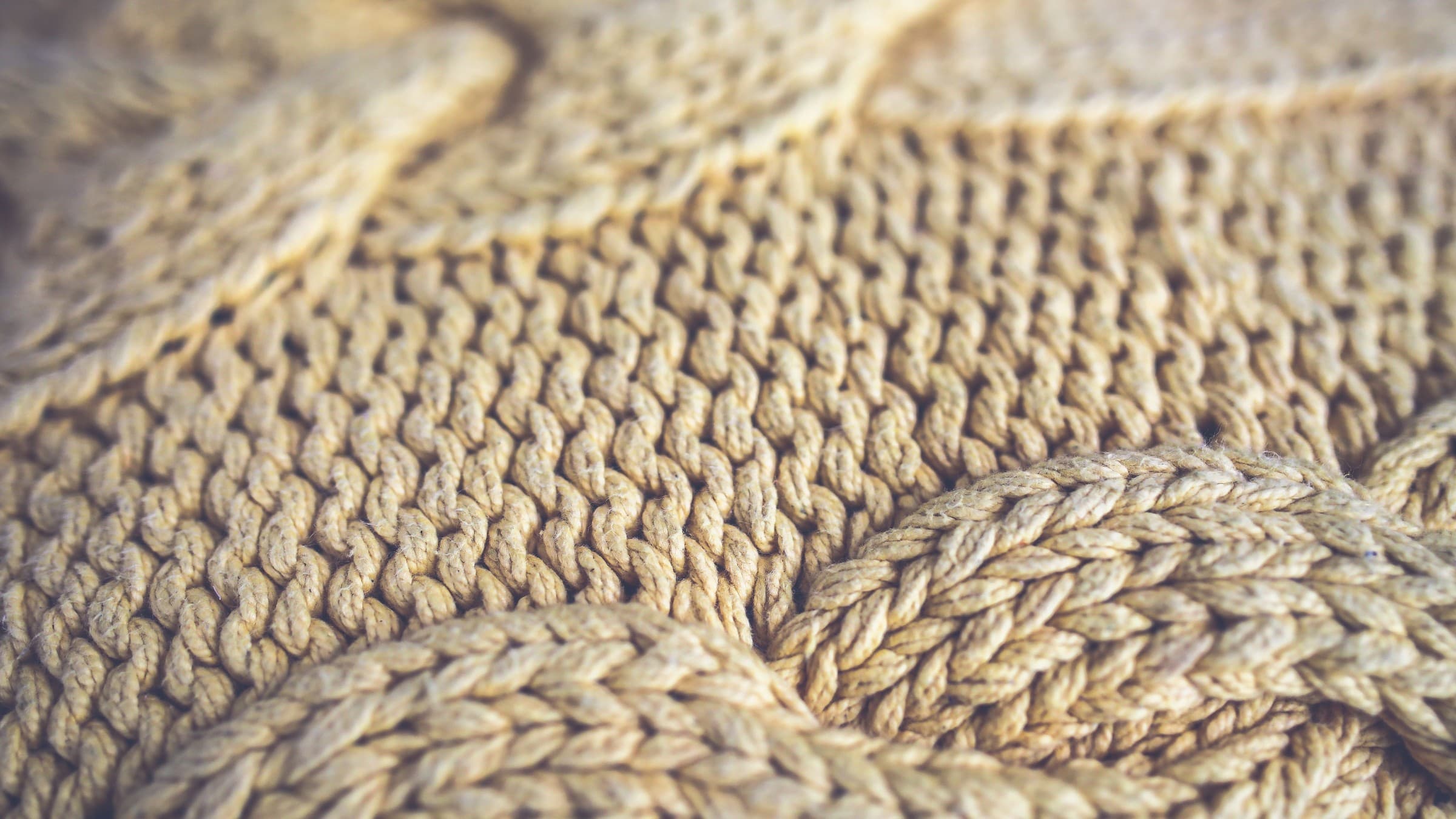 Close up of cream cable knitted wool, the cables running through the lower half of the frame