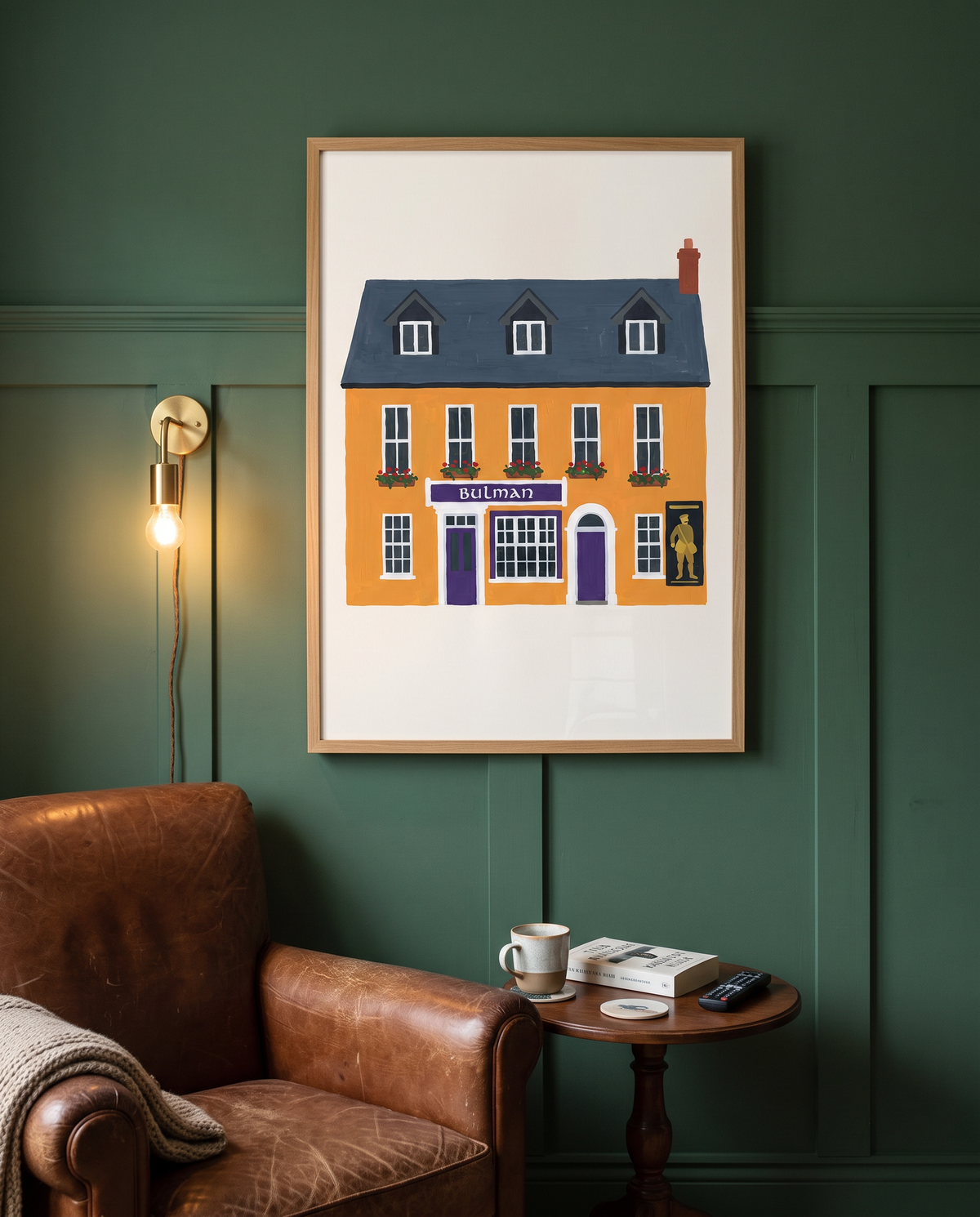 The Bulman, Kinsale, printed and framed in oak on deep green panelling beside a leather armchair