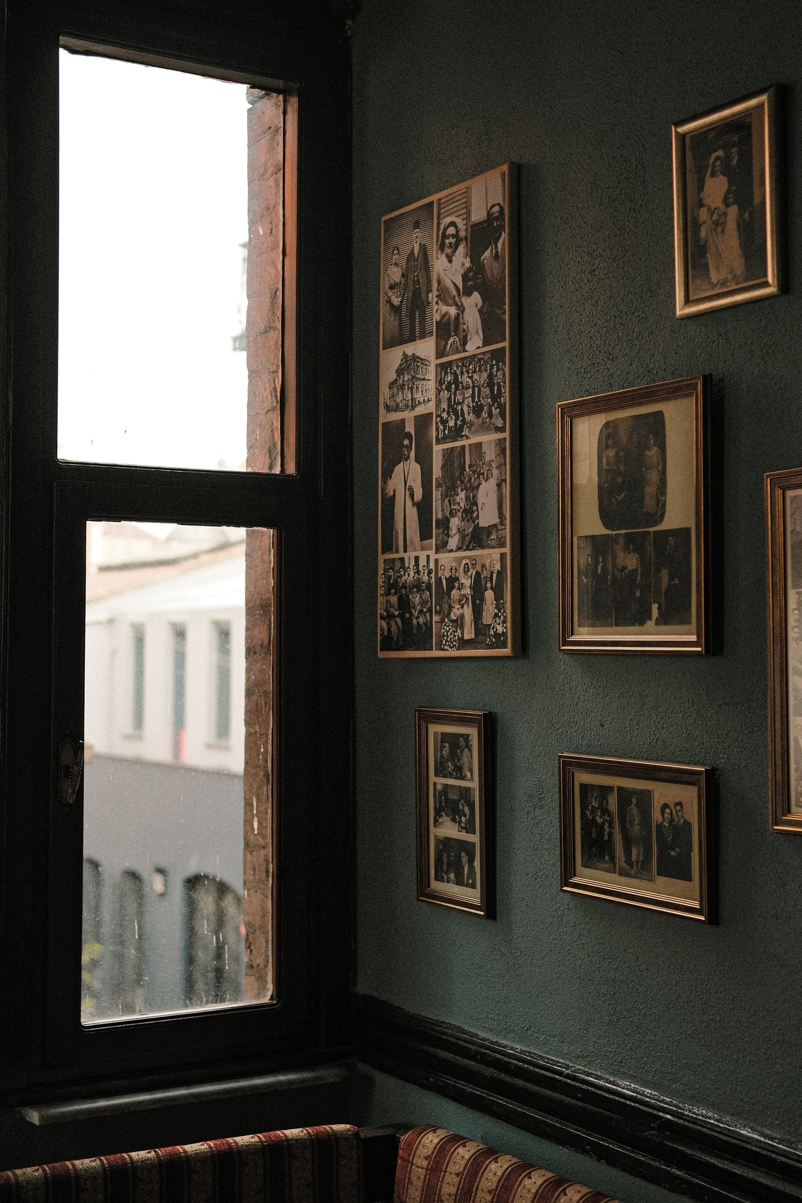 Framed family photographs hung on a deep green wall in an Irish home