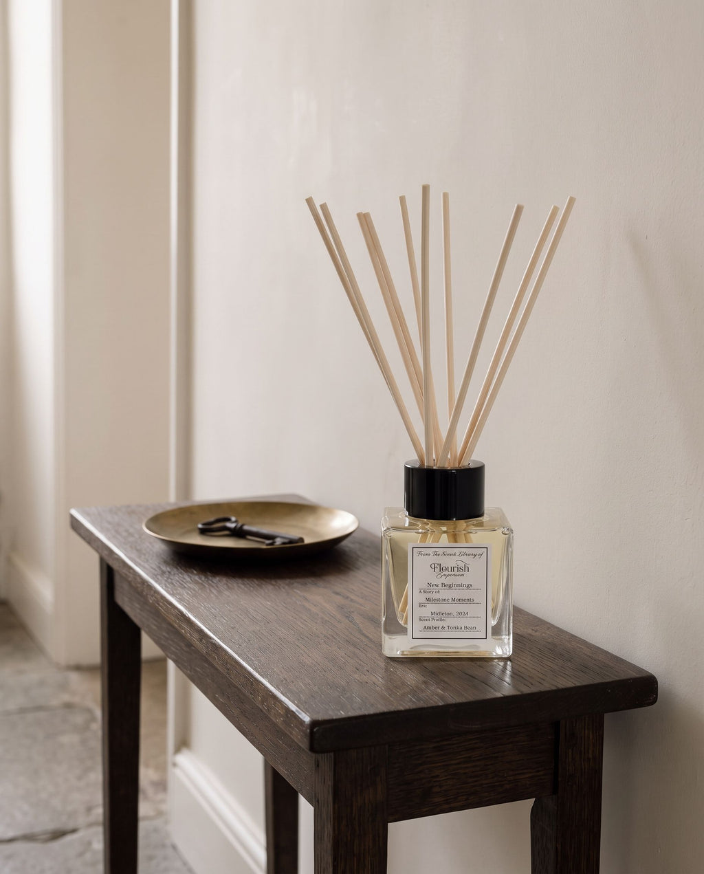 New Beginnings reed diffuser on a dark oak hall console beside a brass dish