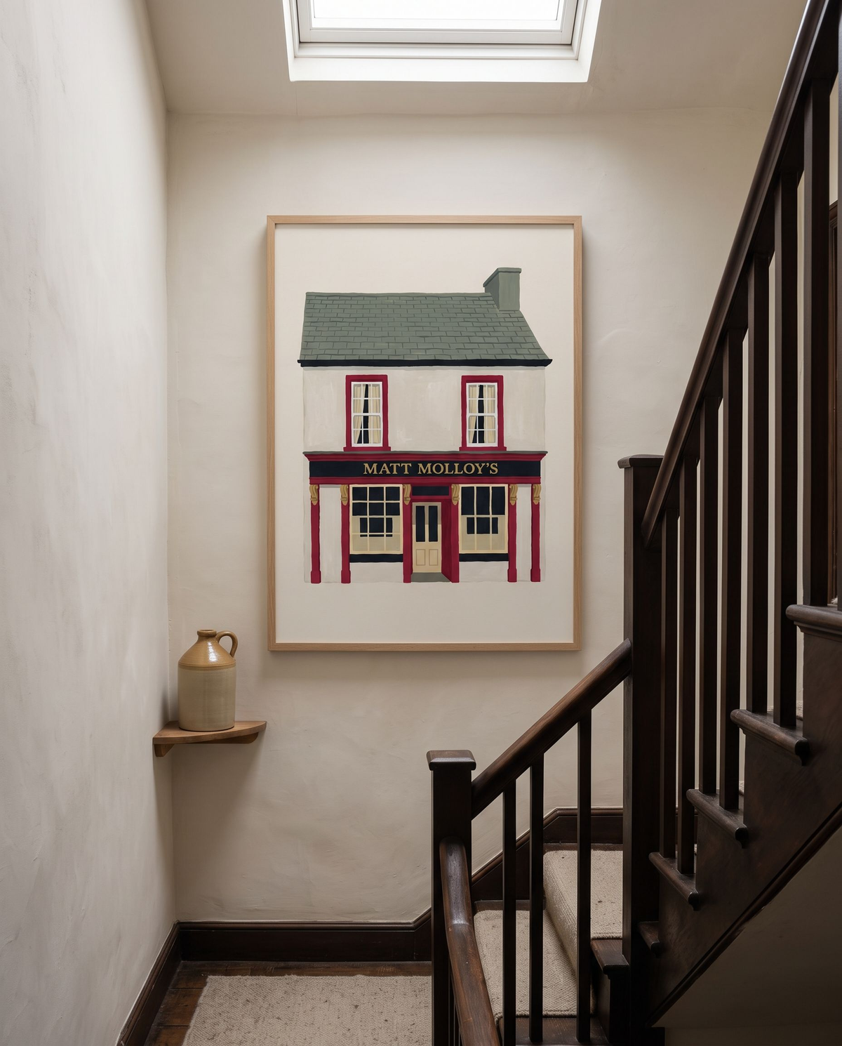 Matt Molloy's print framed in oak on a limewashed stair landing beside a dark timber banister