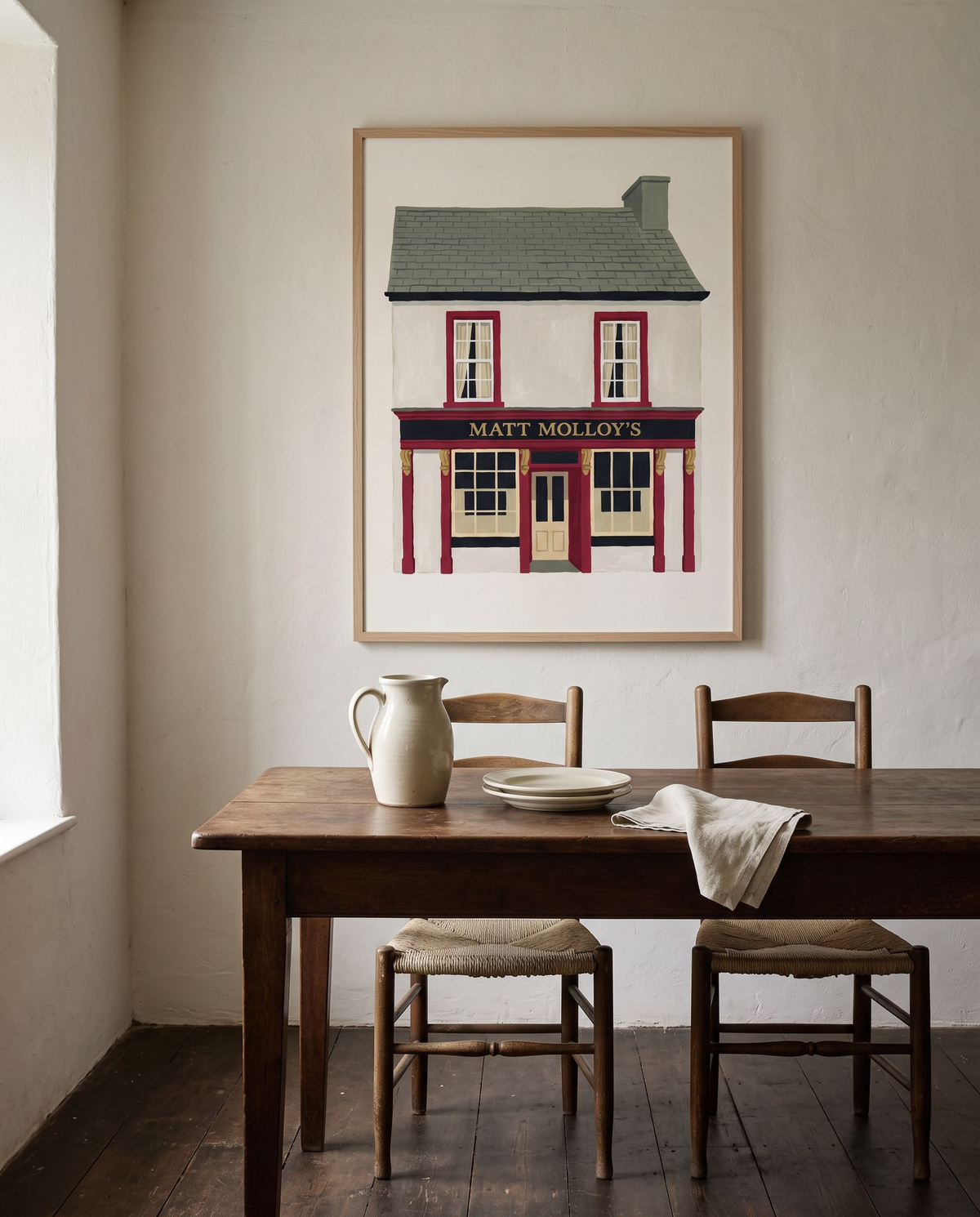 Matt Molloy's print framed in oak above a scrubbed oak dining table with rush-seated ladderback chairs