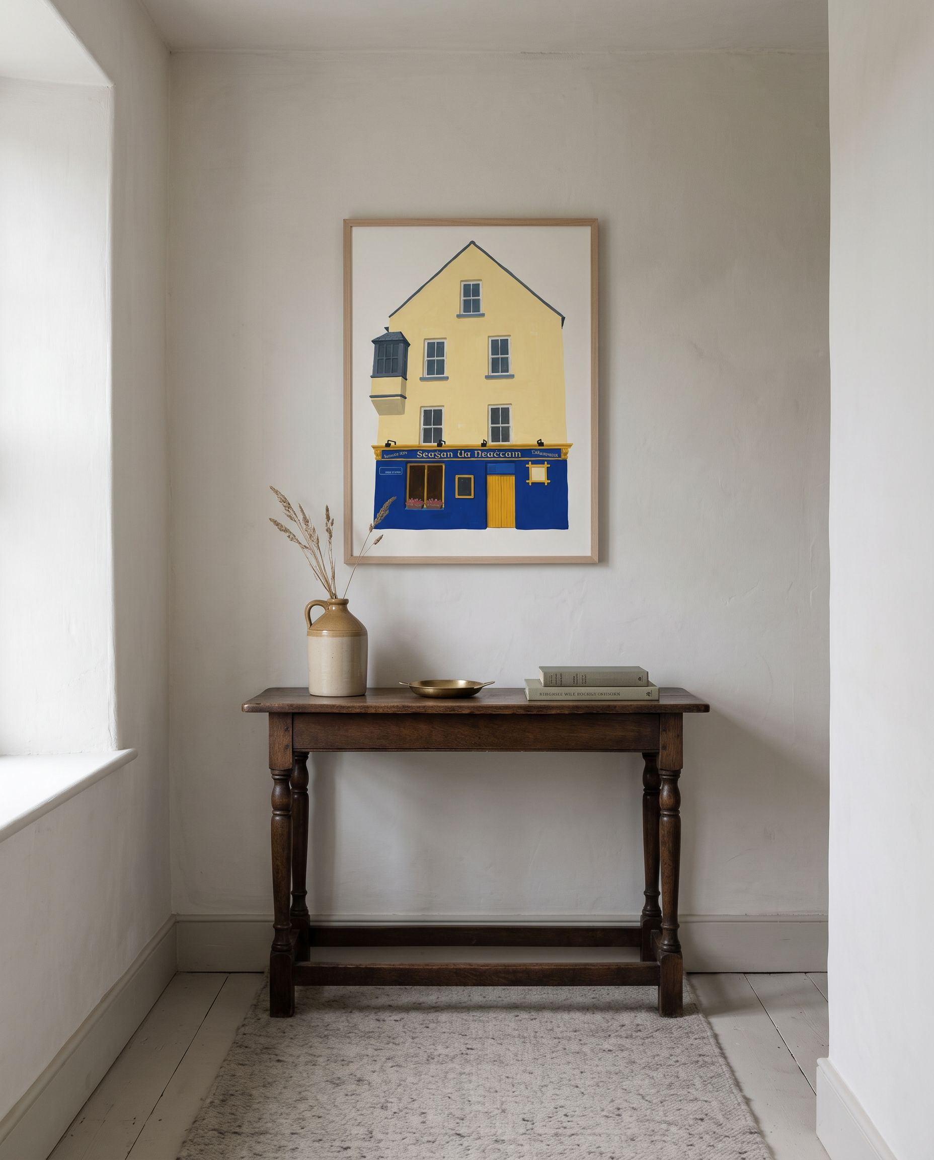 Tigh Neachtáin print framed in oak, hanging above a dark oak console table in a limewashed Irish hallway
